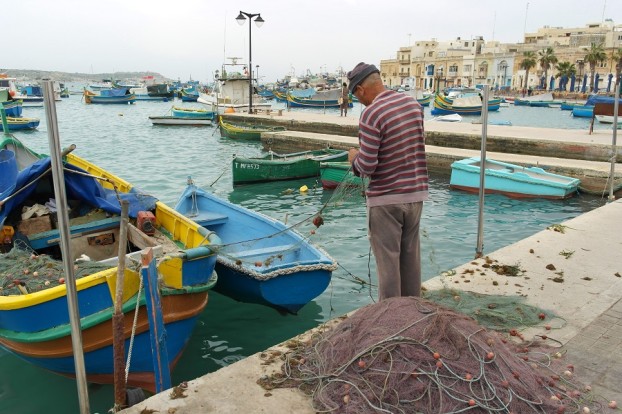 Ein alter Fischer reinigt seine Netze in Marsaxlokk